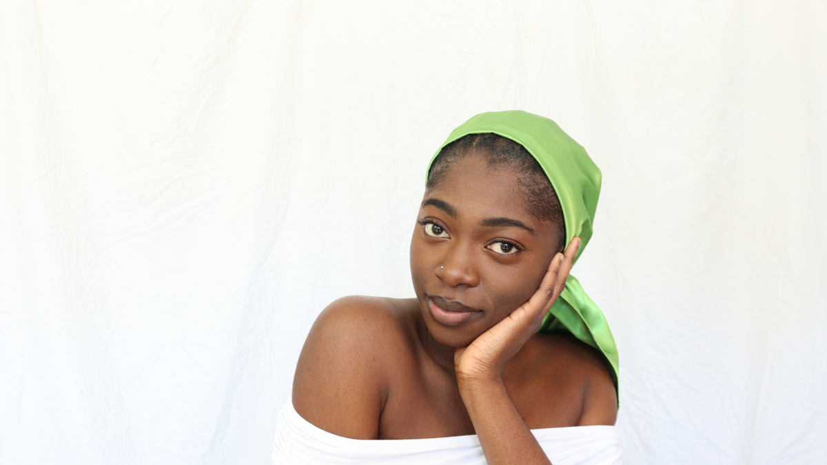 Femme noire regardant de fasse et portant un foulard en satin vert vif nommé Jolene de la collection Sika